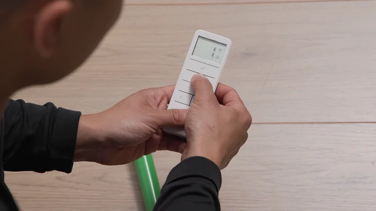 A hand holding the UBlockout remote and pressing a button