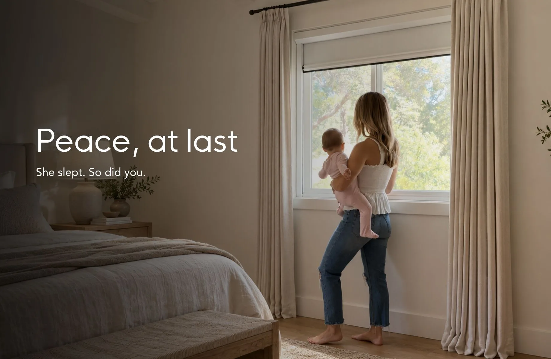 Peace, at last — she slept, so did you. A parent holding a sleeping baby at a bright window with the shade drawn