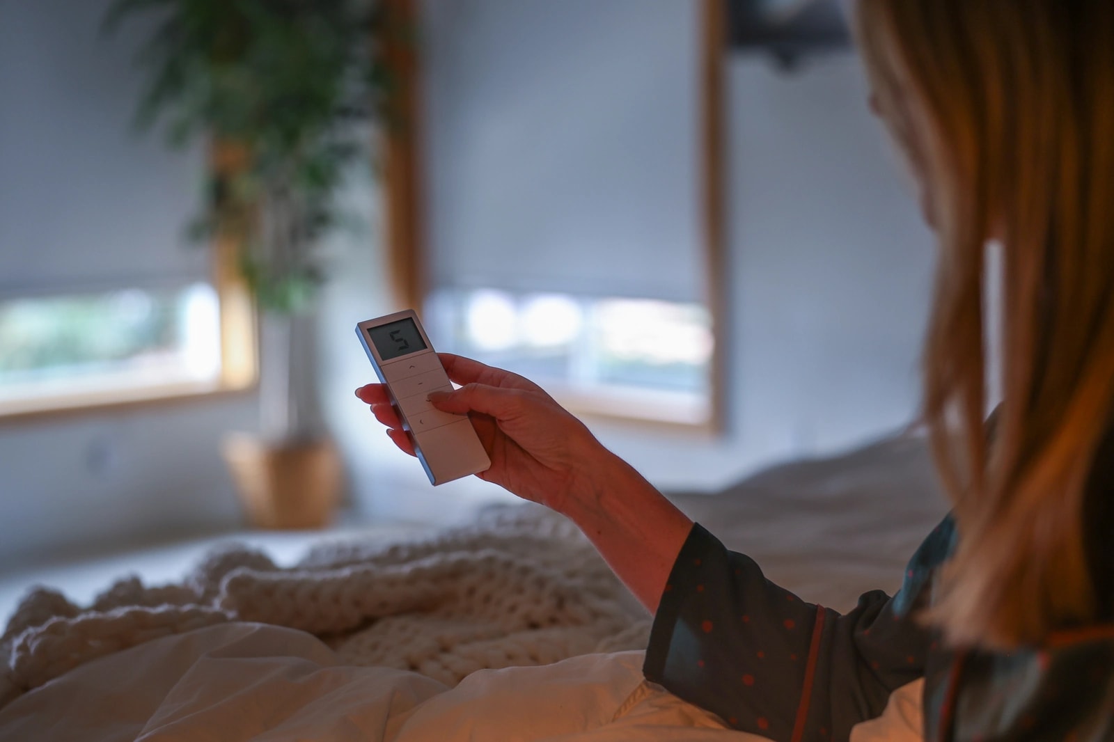 Adjusting the shade by remote from bed, with daylight outside